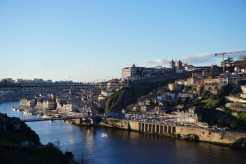 Fototapeta na wymiar This image shows a row of cozy riverside homes in the Ribeira district of Porto, Portugal. The homes are built of stone and wood and have red-tiled roofs. They are located along the banks of the Douro