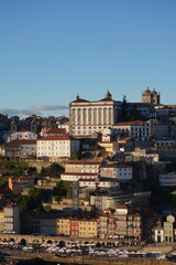 Fototapeta na wymiar This image shows a row of cozy riverside homes in the Ribeira district of Porto, Portugal. The homes are built of stone and wood and have red-tiled roofs. They are located along the banks of the Douro