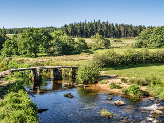 Fototapeta premium Old clapper bridge over the West Dart river at Postbridge, Dartmoor, Devon, UK.