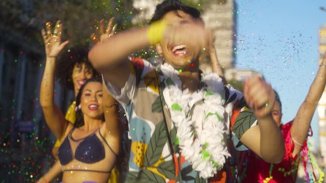 Confetti Rain at Brazilian Carnival, Exhilarating Moment with Smiling Friends in Festive Gear. Unbridled Joy Amidst Street Party with Energetic Dance and Laughter.