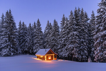 Winter landscape. Panorama with a wooden hut on a meadow covered with snow. New Year's lanterns...