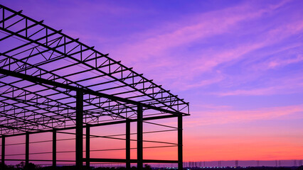 Silhouette metal warehouse outline structure in construction site against colorful twilight sky...
