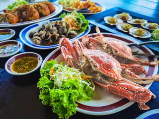 Top view of variety Seafood party table with scallop, cockle, crab, clams, shrimps, crayfish on black background. Seafood platter on black wooden table. Assortment of different seafood with vegetables