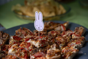 petite étiquette de papier en forme de tète de lapin piqué sur une assiette de bouchées de pizza