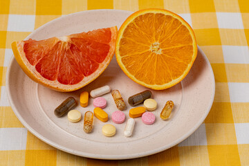 Sliced orange and grapefruit on plate with vitamins and dietary supplements. Organic fruit, healthy diet and nutrition concept.