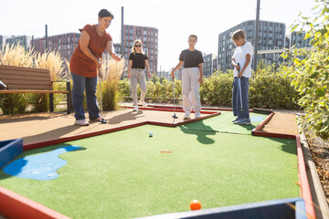 family playing mini golf on a cruise liner. Child having fun with active leisure on vacations.