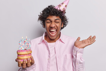 Anniversary celebration concept. Overjoyed Hindu man with curly hair celebrates 25th birthday...