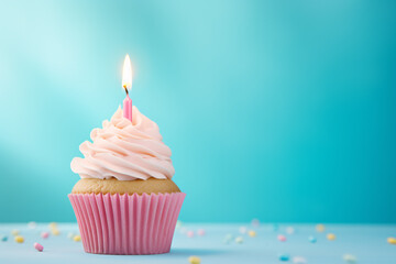 Single cupcake with frosting and pink burning birthday candle in front of blue background