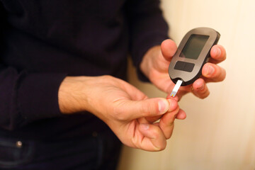 Man inserting blood test strip in glucometer for measurement