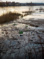 Washed up plastic bottles at the riverbank of a water stream. The river transported disposal waste...