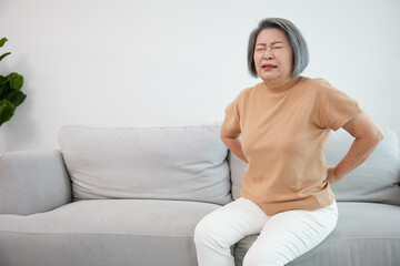 senior woman suffering from back pain on sofa