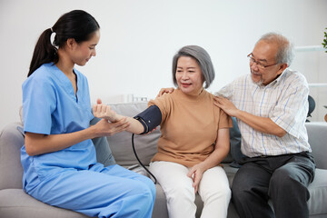 caregiver or nurse measure blood pressure to senior woman on sofa