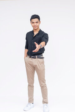 A friendly and handsome Filipino man offering his hand for a handshake. Wearing black polo shirt and khaki pants. Full body photo, isolated on a white background.