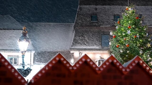 Slowmotion of many snowflakes flying through christmas market and christmas tree.
