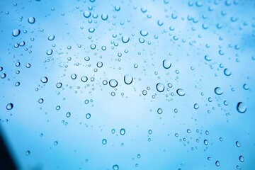 Close up rainwater drop on glass with blue sky background, wallpaper, bubbles, natural, water 
