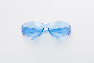 Safety glasses on color background, top view
