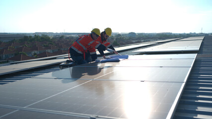 Engineer and technician working on the solar panel on the warehouse roof to inspect the solar panels that have been in operation for some time.
