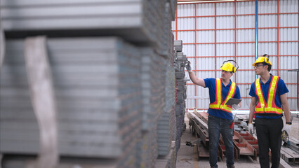 Warehouse workers in hard hats and helmets, Inspect and count steel in the warehouse.