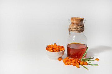 A bottle of sea buckthorn oil and sea buckthorn berries on a white background. Healing oil making concept