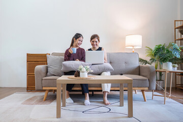 Two woman communicate with their friends and classmate via video link using a laptop and smartphone in the living room. Friends, friendship, time together
