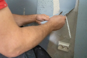 Man Skillfully Renovates Bedroom, Removing Glassfiber Wallpaper for a Refreshed Ambiance.
