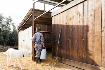 Woman with milk churn opening barn doors