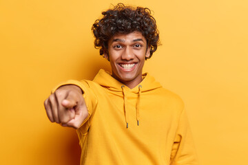 I choose you. Cheerful handsome Hindu man with curly hair pointing finger at camera with happy face...