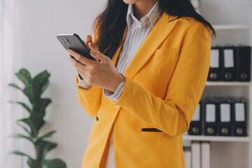 Young smiling business woman using smartphone near computer in office, copy space