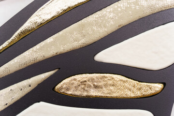 Patterned texture with pieces of leather in white, gold and black used as a classic background.