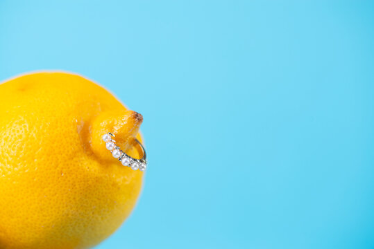 Intimate piercing. Minimal piercing concept. Lemon with inserted iron decoration, piercing