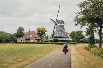 Frau passiert während einer Fahrradtour durch die Niederlande eine typische holländische Windmühle