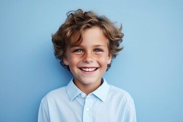 Portrait of a cute little boy smiling at the camera on a blue background