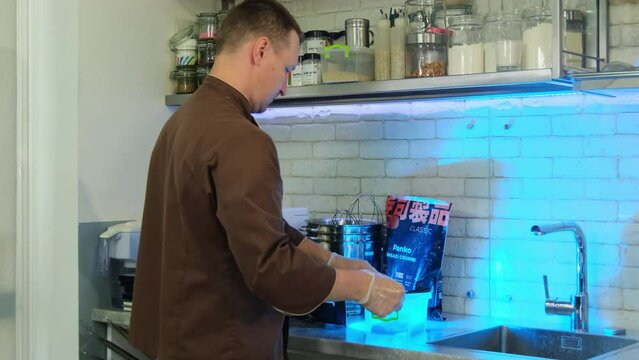 Male chef retrieves straws from tray preparing to craft culinary masterpiece using meat paste and straws. Making craft dish concept