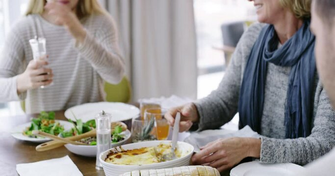 People, hands and dishing food for eating, dining or meal together on living room table at home. Closeup of happy and hungry family sharing dinner, snack or lasagne on plate with salad for nutrition