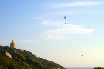 Fototapeta na wymiar paraglider flying above the Atlantic Ocean near the Faro de Camarinal lighthouse near Atlanterra during the sunset, Costa de la Luz, Andalusia, Spain, extreme sport, paragliding, freedom, activity