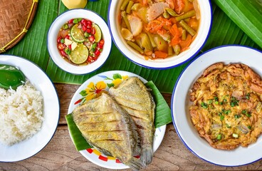 Traditional Thai food set Rice with THAI OMELET and fried  gourami fish with hot and sour curry and thai stylr sauce, top view food table