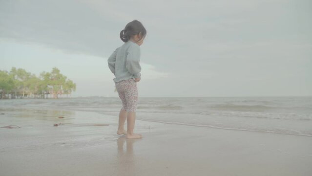The child happily plays in the waves on the seashore. A girl playing in the waves on the beach. S-log, ungraded