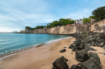 Historic walls along the coastline and small beach in Old San Juan, Puerto Rico.