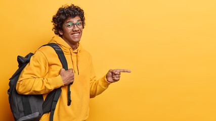 Horizontal shot of handsome curly haired Hindu man wears transparent eyeglasses and casual hoodie...