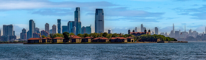 Photograph of Ellis Island, from Liberty Island where the iconic statue of New York (USA) is located and the Big Apple skyline in the background.