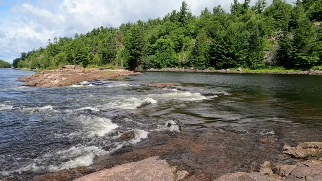 Small waterfall on river in northern wilderness, pan left.
