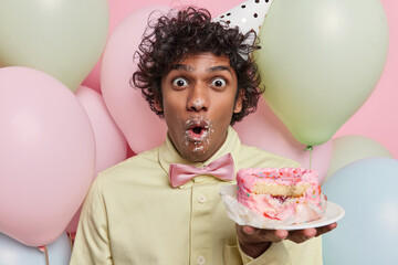 Photo of impressed Hindu man with curly hair wears festive clothing holds plate with delicious...