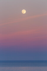 Peaceful sunset in pastel tones with a full moon over the Cantabrian Sea