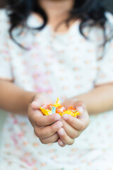 Closeup image of a asian child, girl 3 years holding colorful candy sweets in hands. happy childhood, balanced diet, sweet life, unhealthy food.
