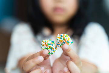 Closeup image of a asian child, girl 3 years holding colorful gelatinous sweets, Jelly gum in hands. happy childhood, balanced diet, sweet life, unhealthy food.
