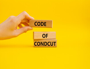 Code of conduct symbol. Wooden blocks with words Code of conduct. Beautiful yellow background. Businessman hand. Business and Code of conduct concept. Copy space.