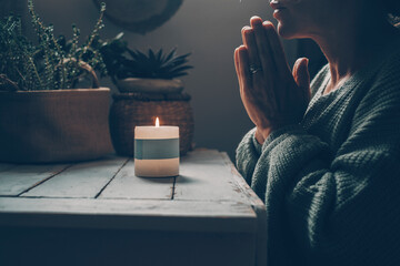 Christian woman kneeling and praying near candles. He seeks guidance in his religious faith and...