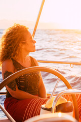 Woman traveling by boat at sunset among the oceans - happy and free modern alternative lifestyle...