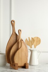 Wooden cutting boards, kitchen utensils and dishware on white marble table