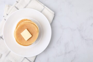 Delicious pancakes with butter on marble table, top view. Space for text